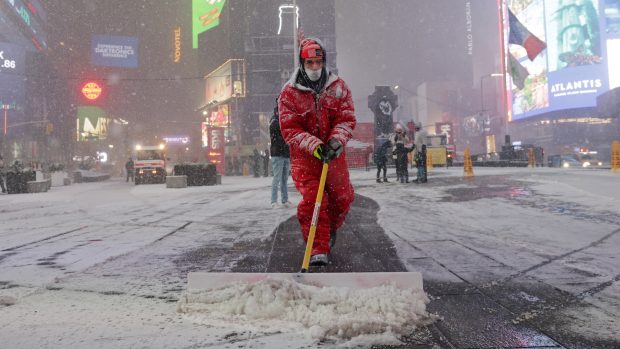 Muž odklízí sníh z chodníku na Times Square v newyorské části Manhattan
