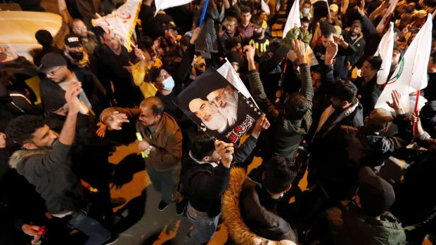 Během připomínkové akce se sešly davy lidí nejen v Iránu, ale také v Bagdádu. Na fotografii drží muž transparent s podobiznami šíitských vůdců Chameneího a Chomejního