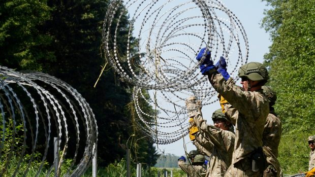Litevští vojáci pokládají na hranicích s Běloruskem ostnatý drát na obranu proti migrantům.
