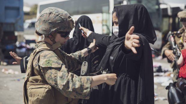 Příslušnické americké námořní pěchoty prohledává Afghánku na letišti v Kábulu