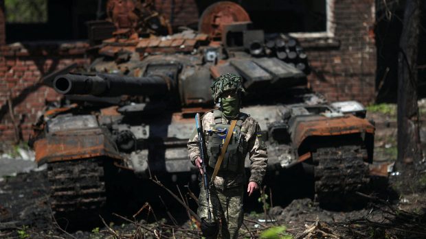 Ukrajinský voják před zničeným ruským tankem poblíž Charkova