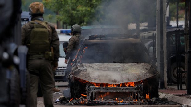 Příslušníci speciálních policejních jednotek stojí u hořícího auta po střetech mezi kosovskou policií a protestujícími etnickými Srby