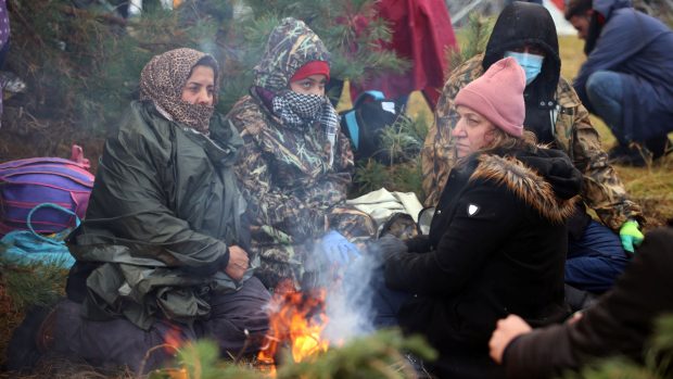 Skupina žen na bělorusko-polské hranici se snaží zahřát u ohně