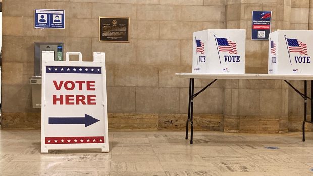 Manažeři voleb nasměrují voliče do jedné z hlasovacích budek, kde si mohou v soukromí lístky upravit