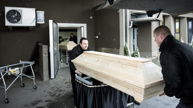 Rakev s tělem je po vyložení auta postavena na vozík a převezena do krematoria