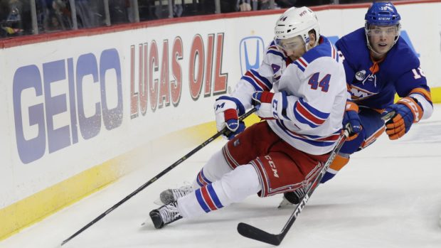 Neal Pionk hrající za New York Rangers si kryje puk před Anthony Beauvillierem z Islanders