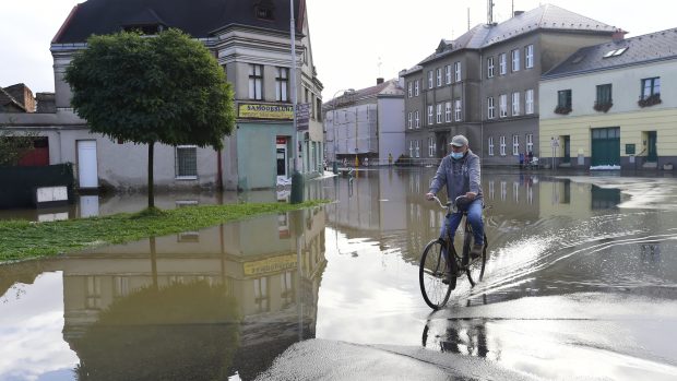 Cyklista projíždí zaplavenou ulicí v Brodku u Přerova, kde se po intenzivních deštích vylila z břehů říčka Olešnice. Fotografie z 15. října