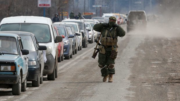Příslušník proruských jednotek prochází podél řady aut s evakuovanými, kteří opouštějí obležené jihoukrajinské přístavní město Mariupol