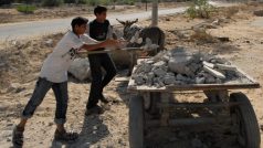 Palestinští chlapci nakládají na vozík beton