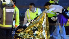 Policisté a záchranáři nad obětí nehody ve španělské Castelldefels Playa, kde při železničním neštěstí zahynulo 12 lidí.