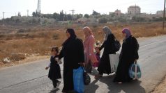 Palestinky procházejí kolem židovské osady v arabském Hebronu. Jejich muži tam možná pracují.