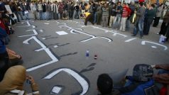 Egyptští demonstranti stojí v centru Káhiry nad arabským nápisem „Odejdi, zbabělče, my náměstí neopustíme“