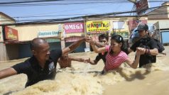 Dobrovolníci pomáhají lidem v povodňovém proudu v ulicích filipínského města Calumpit po úderu tajfunu Nesat