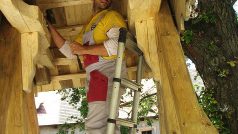 Dělník umisťuje velký zvon na tesanou dřevěnou zvoničku