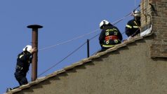 Hasiči připevňují komín na střechu Sixtinské kaple, který bude signalizovat zvolení či nezvolení papeže