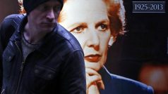 Muž prochází kolem plakátu zesnulé Margaret Thatcherové s oběma letopočty jejího života