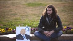 Mladý Izraelec s portrétem Ariela Šarona poblíž rakve zesnulého premiéra, která byla vystavená u izraelského parlamentu
