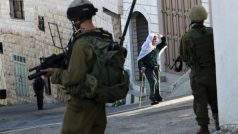 Palestinská žena prochází kolem izraelské hlídky v Nábulusu
