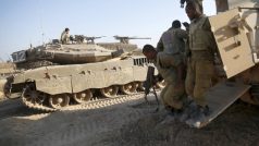 Izraelský voják vystupuje z obrněného transportéru, který stojí vedle tanku