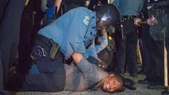 Policista zatýká jednoho z protestujících před stanicí ve Fergusonu