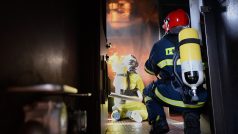 První dvojice hasičů vstupuje do hořící místnosti. Nejdříve prostor schladili několika krátkými pulzy z proudnice