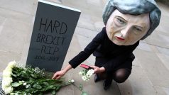 Někteří už mají o osudu &quot;tvrdého brexitu&quot; jasno - neprojde. Demonstrantka proti Therese Mayové s maskou britské premiérky na hlavě pokládá květiny k symbolickému náhrobku před Downing Street. Povolební pátek, Londýn.