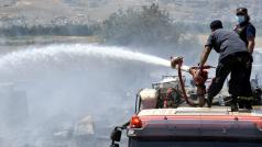 Příslušníci civilní ochrany dohašují požár uprchlického tábora v Libanonu.