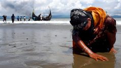 Vyčerpaná rohingská žena se dotýká země po vylodění z plavidla, jímž spolu s dalšímu uprchla z Barmy do Bangladéše.