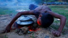 Uprchlý rohingský chlapec rozfoukává oheň pod jídlem v jednom z provizorních utečeneckých táborů v Bangladéši.