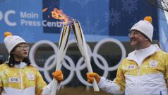 Dobrovolníci si předávají olympijský oheň