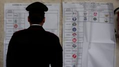 Italský policista zkoumá plakát s politickými stranami u volební místnosti v Římě (4. března 2018).