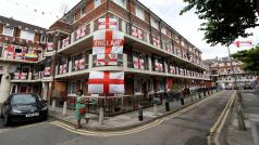 Žena kráčí kolem budovy ozdobené anglickými vlajkami při příležitosti fotbalového šampionátu