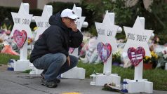 Muž klečící u pomníků obětí střelby v Pittsburghu.