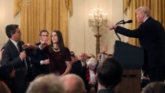 Reportér CNN Jim Acosta (vlevo) nechce předat mikrofon asistentce poté, co mu prezident Donald Trump (za řečnickým pultem) odmítl odpovědět na otázku.