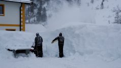 Dva muži odklízejí sníh po sněhové vánici v rakouském lyžařském centru Obertauern