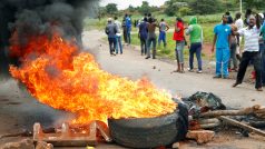 Demonstranti nedaleko hořící barikády před Harare na snímku z 15. ledna 2019.