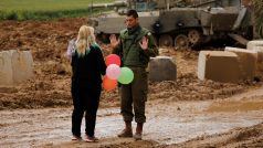 Žena dává poblíž hranice s Pásmem Gaza izraelskému vojákovi balónky, snímek agentury Reuters