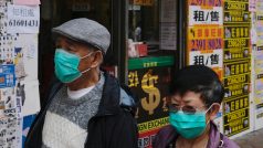 Lidé s ochrannými maskami prochází kolem zavřených obchodů v Hongkongu