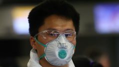Cestující s leteckou společností Air China se na frankfurtském letišti chrání respirátorem