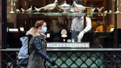 Žena s rouškou před obchodem v centru Londýna na Piccadilly Circus