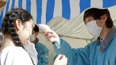 Zdravotník kontroluje teplotu lidí v japonském Tokiu
