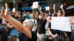 Lidé v Hongkongu zvedají nad hlavu bílý papír, aby neukazovali žádný ze sloganů, které jsou novým bezpečnostním zákonem zakázány. Před budovou soudu tak ukazují solidaritu se zatčenými demonstranty.