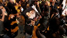 Během připomínkové akce se sešly davy lidí nejen v Iránu, ale také v Bagdádu. Na fotografii drží muž transparent s podobiznami šíitských vůdců Chameneího a Chomejního