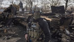 Ukrajinský voják před vrakem ruského tanku na předměstí Kyjeva