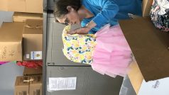 Dobrovolnice vkládá oblečení pro uprchlíky do krabic