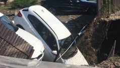Do kaverny vzniklé po prasklém přivaděči vody v Dolních Počernicích se propadly dva automobily.