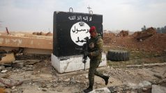 Irácký voják kráčí kolem zdi s namalovanou vlajkou Islámského státu (Mosul v lednu 2017)