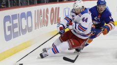 Neal Pionk hrající za New York Rangers si kryje puk před Anthony Beauvillierem z Islanders