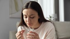 Žena s potratovou pilulkou a sklenicí vody (ilustrační foto)