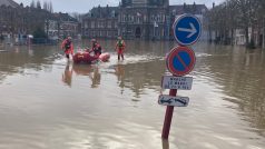 Záchranáři evakuují starší ženu v zatopené obci Arques na severu Francie